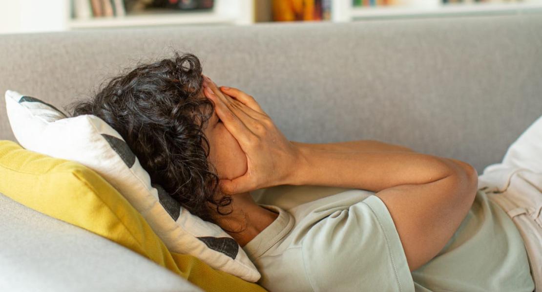 Woman laying on couch with head in hands Woman laying on couch with head in hands