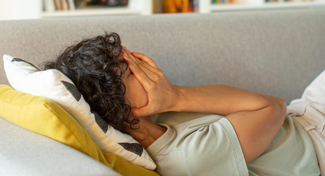 Woman laying on couch with head in hands