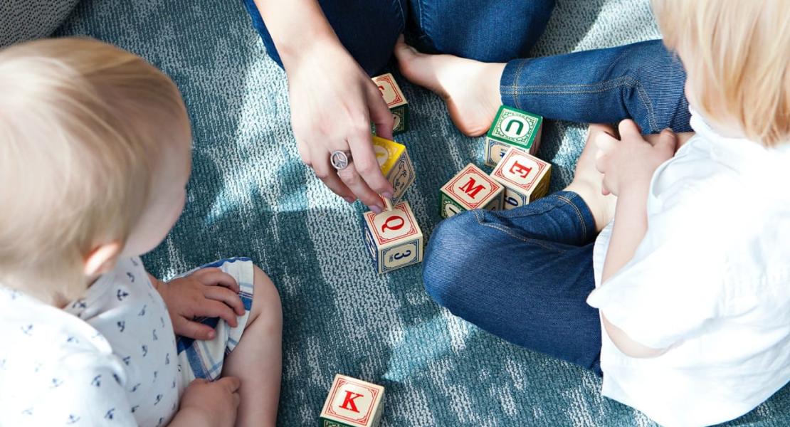 Adult playing with wooden blocks with 2 your children