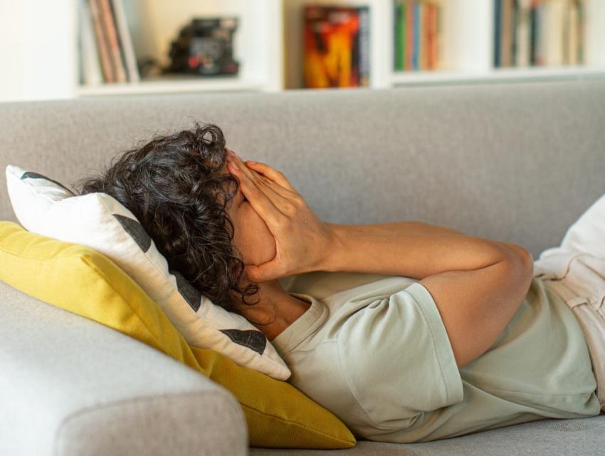 Woman laying on couch with head in hands